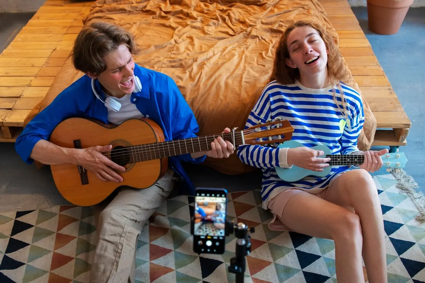 Парень и девушка-подростки записывают музыку в своей домашней студии с гитарой.